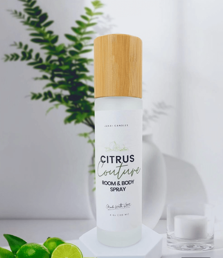 Room and body spray bottle with a wooden cap on a white surface with greenery in the background
