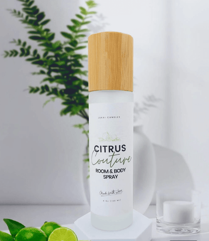Room and body spray bottle with a wooden cap on a white surface with greenery in the background