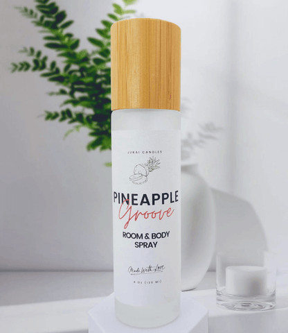 Room and body spray bottle with a wooden cap on a white surface with a plant in the background